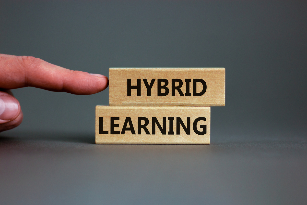 Hybrid learning symbol. Concept words 'Hybrid learning' on wooden blocks on a beautiful grey background. Businessman hand. . Business, educational and hybrid learning concept, copy space.